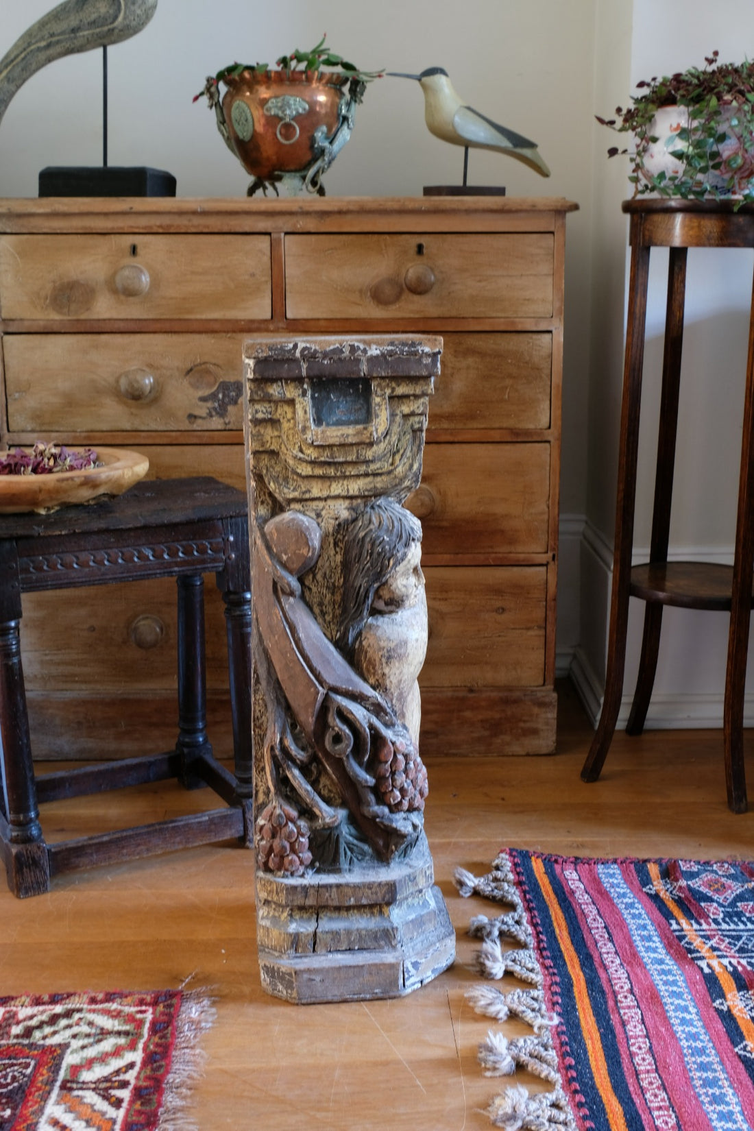 19th-century carved polychrome putto pedestal sculpture with grape motif