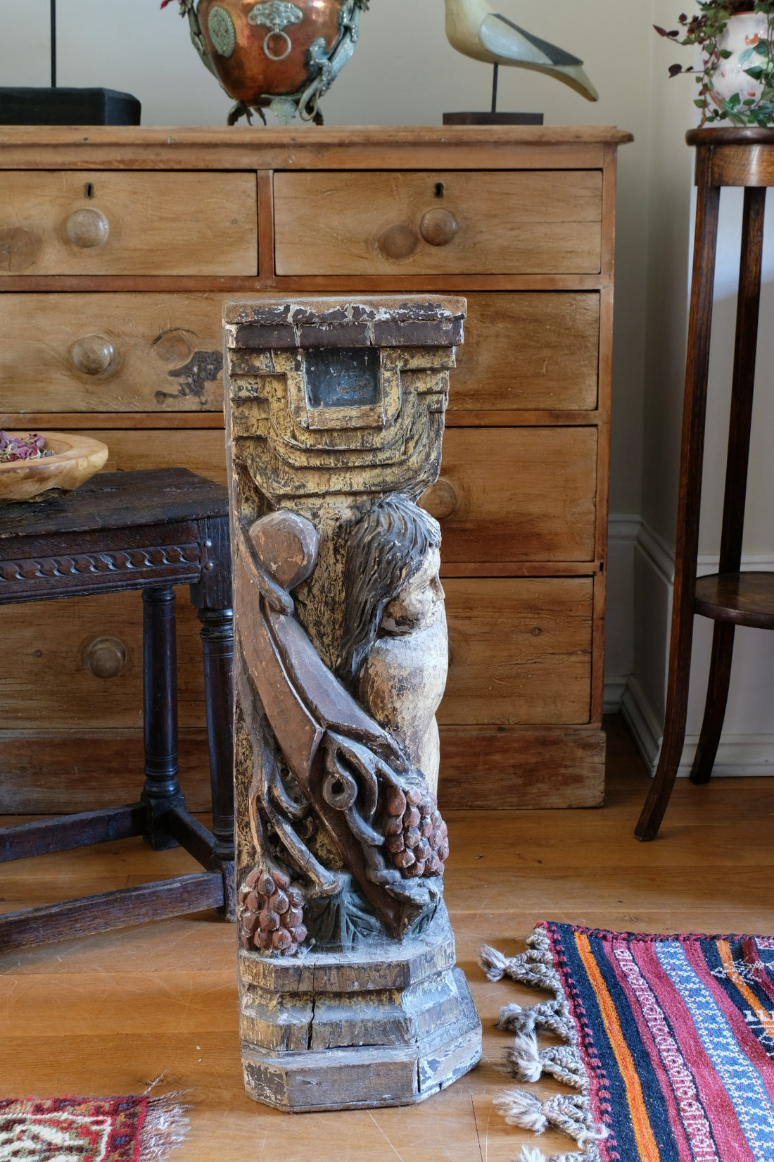 19th-century carved polychrome putto pedestal sculpture with grape motif
