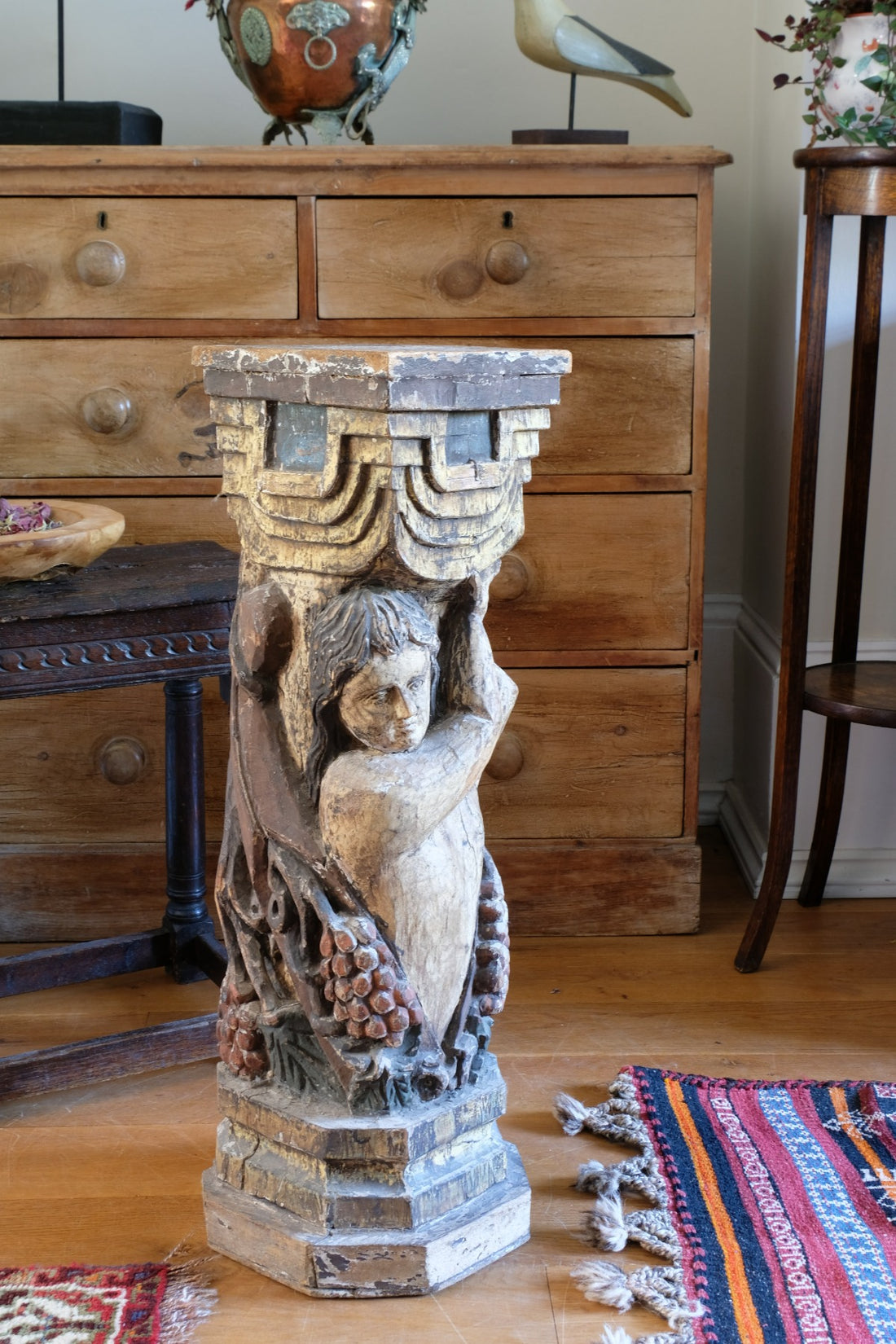 19th-century carved polychrome putto pedestal sculpture with grape motif