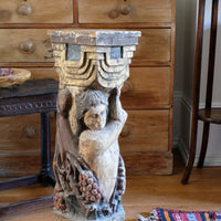 19th-century carved polychrome putto pedestal sculpture with grape motif