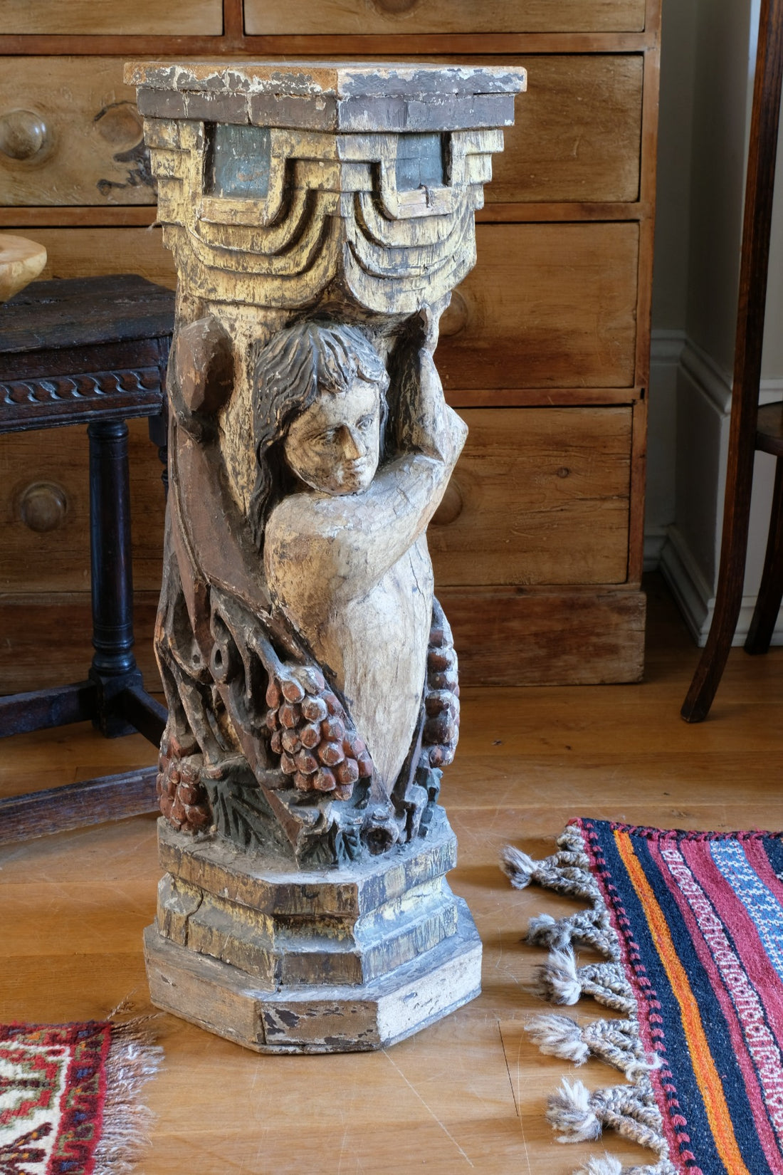 19th-century carved polychrome putto pedestal sculpture with grape motif