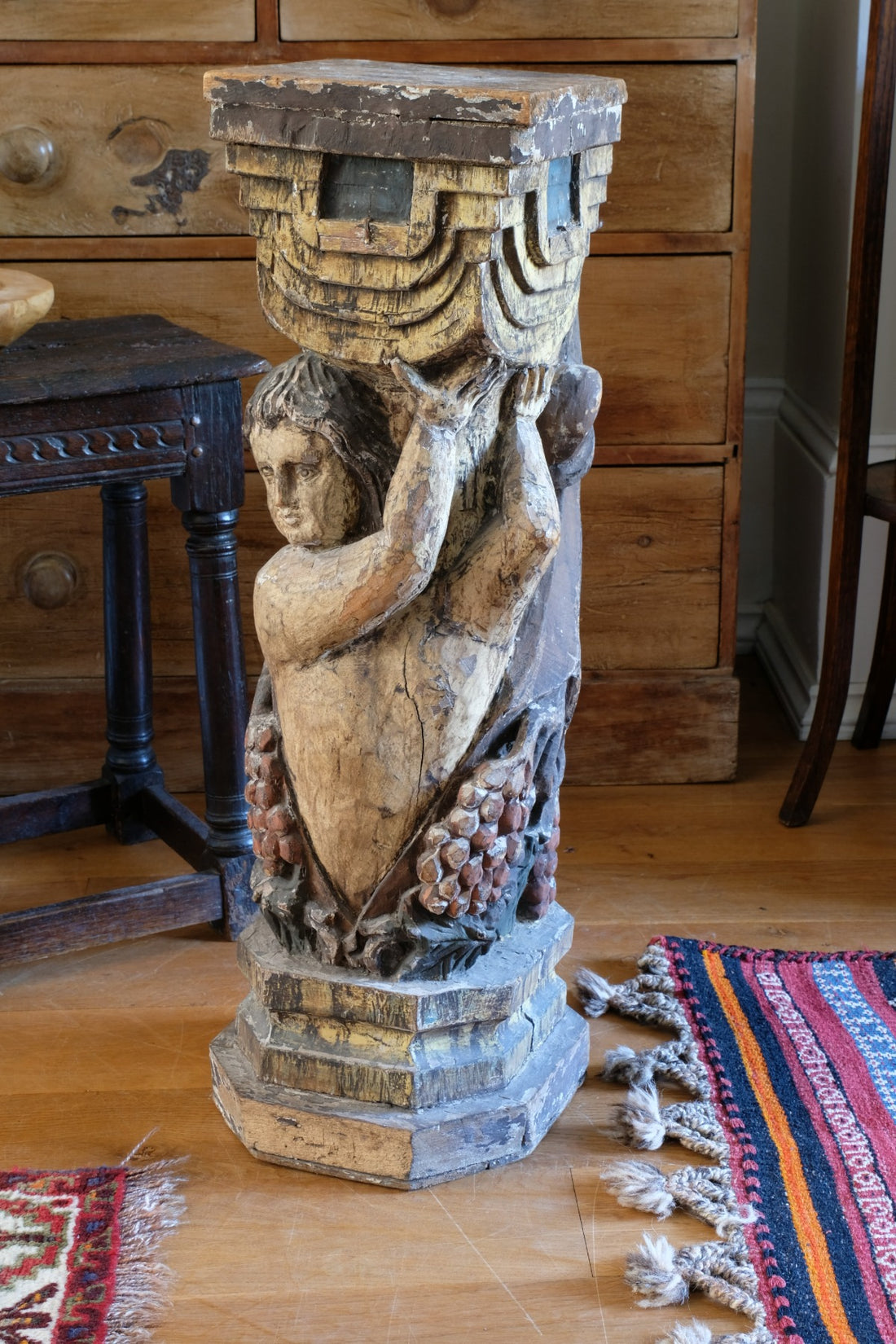 19th-century carved polychrome putto pedestal sculpture with grape motif