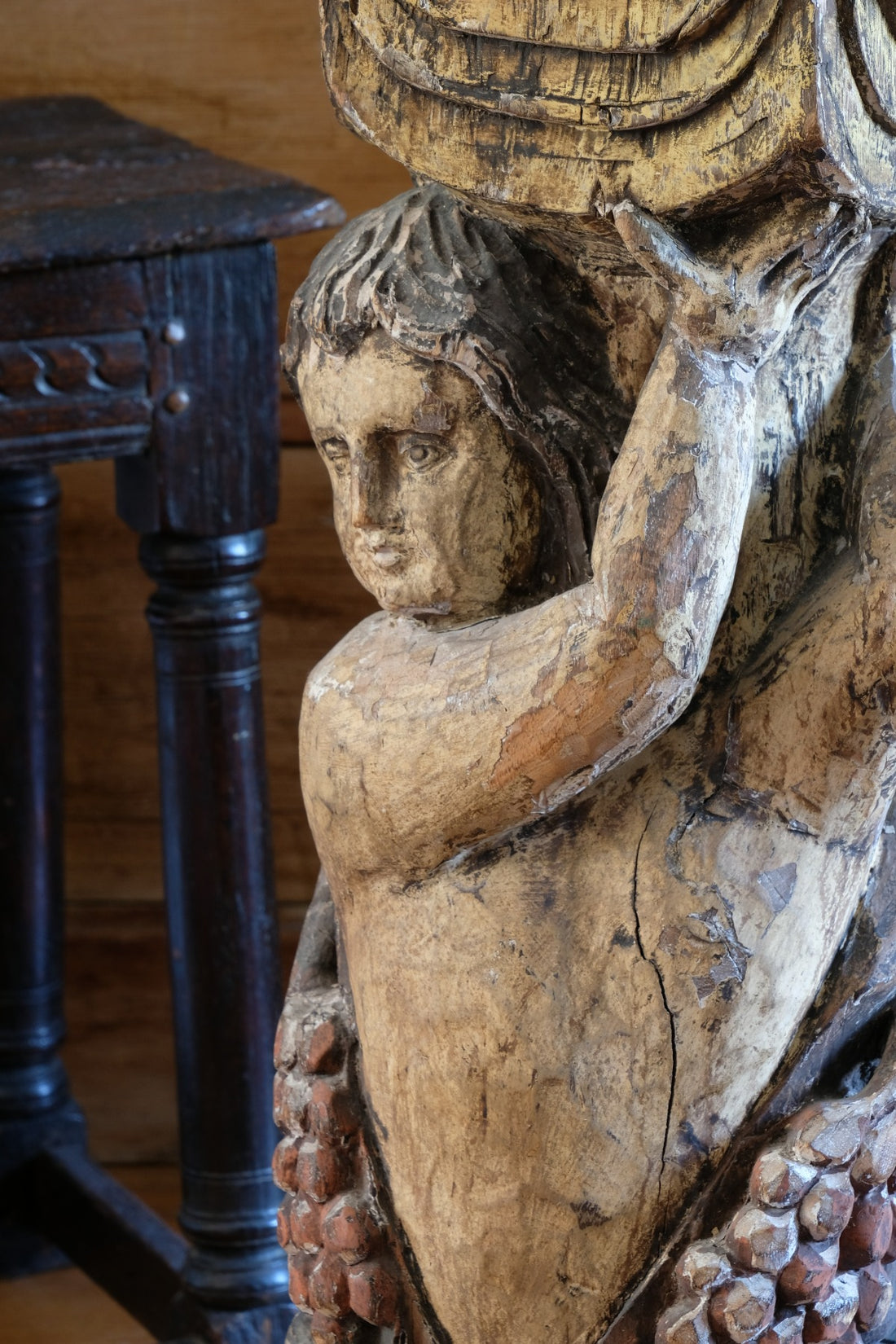 19th-century carved polychrome putto pedestal sculpture with grape motif