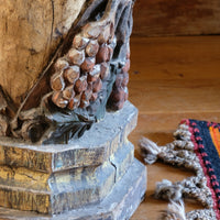 19th-century carved polychrome putto pedestal sculpture with grape motif