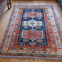 Handwoven Caucasus Kazak wool rug with shield medallions on blue ground
