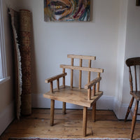 Primitive handmade wooden armchair with rustic timber finish and blocky carved design