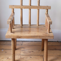 front view - Primitive handmade wooden armchair with rustic timber finish and blocky carved design