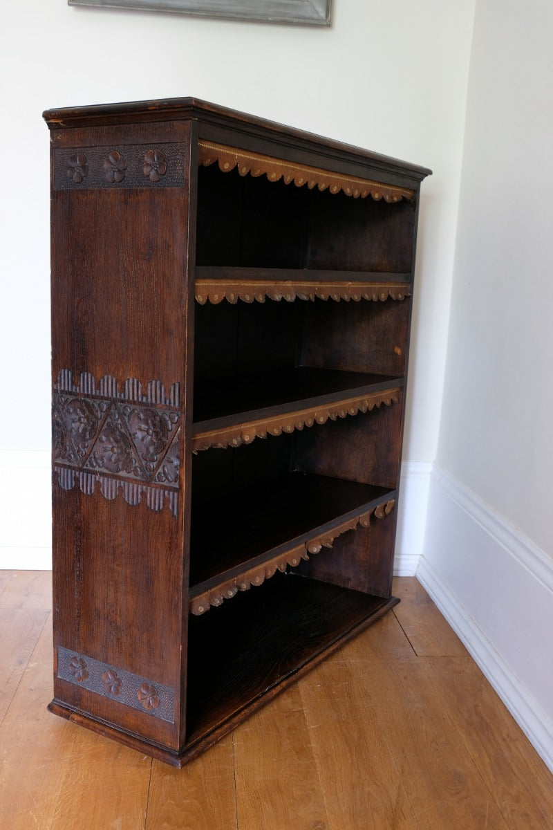 Edwardian carved oak bookcase with leather dust cover fringes