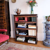Edwardian Arts and Crafts carved oak bookcase with original tooled leather dust fringing shelves