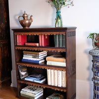 Side view detail of carved arts & crafts end panels - Edwardian Arts and Crafts carved oak bookcase with original tooled leather dust fringing shelves