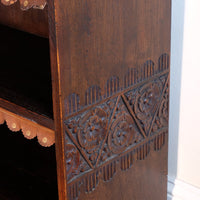 lower chip carved view of a Edwardian Arts and Crafts carved oak bookcase with original tooled leather dust fringing shelves