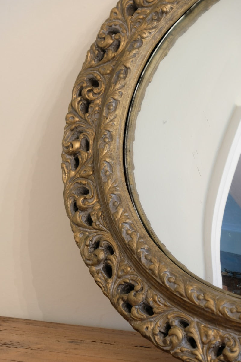 Close‑up carved giltwood foliate detail on convex mirror frame