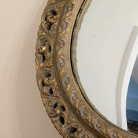 Close‑up carved giltwood foliate detail on convex mirror frame