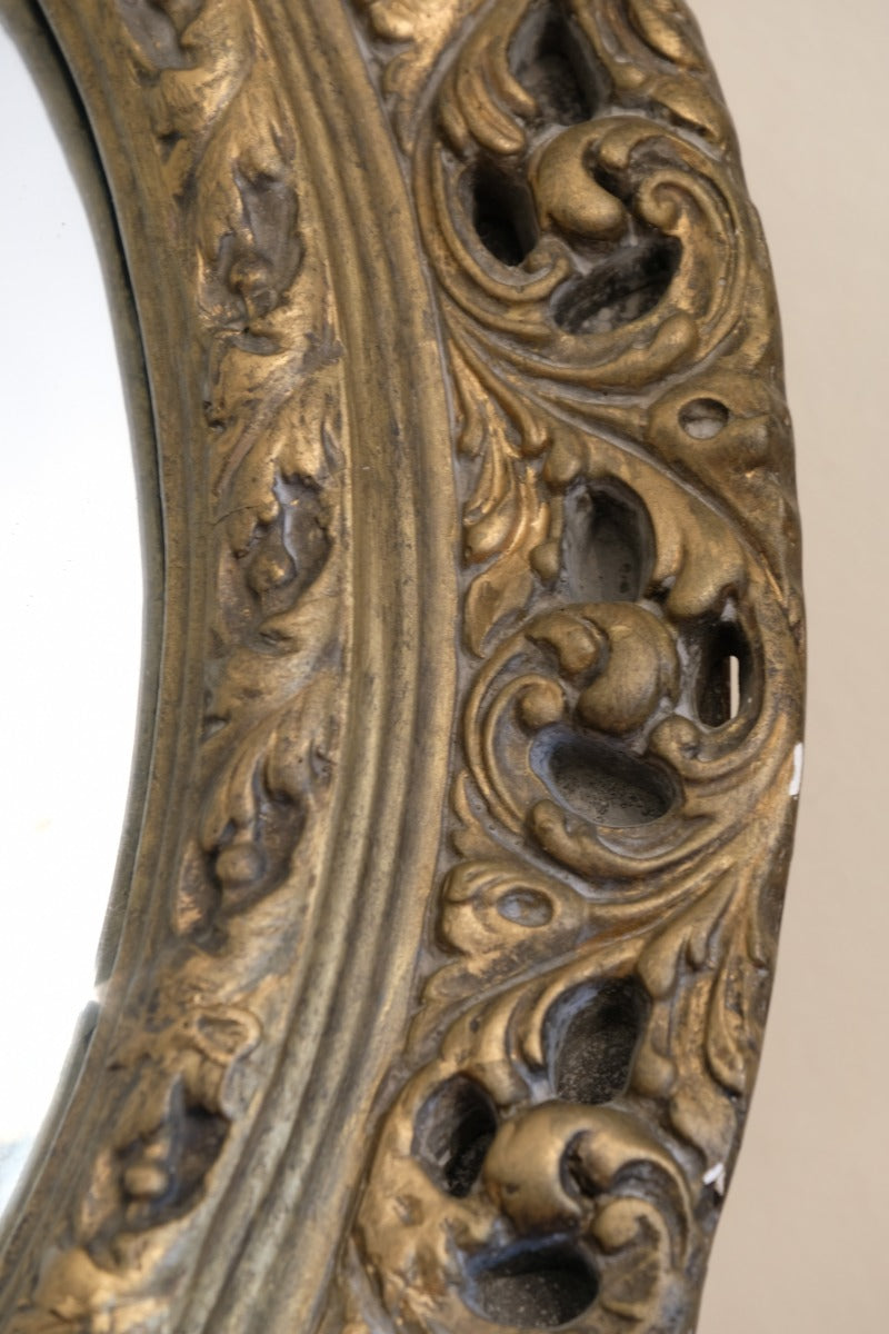 Close‑up carved giltwood foliate detail on convex mirror frame