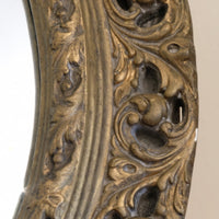 Close‑up carved giltwood foliate detail on convex mirror frame