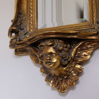 Close up of a Late Victorian gilt wall mirror with original bevelled mirror plate and cherub shelf detail