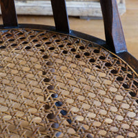Close up view of the cane seat on a Rare Edwardian bentwood lattice back armchair attributed to Jas Shoolbred with pierced Arts & Crafts design