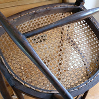 Underneath of a View of the cane seat on a Rare Edwardian bentwood lattice back armchair attributed to Jas Shoolbred with pierced Arts & Crafts design