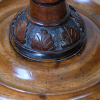 Close up of the carved oak leaves on a carved foliate collar, adding further depth and refinement before transitioning into a substantial circular platform base. Rare Victorian walnut barley twist candle and wine stand with brass candle sconce and carved foliate decoration, circa 1870