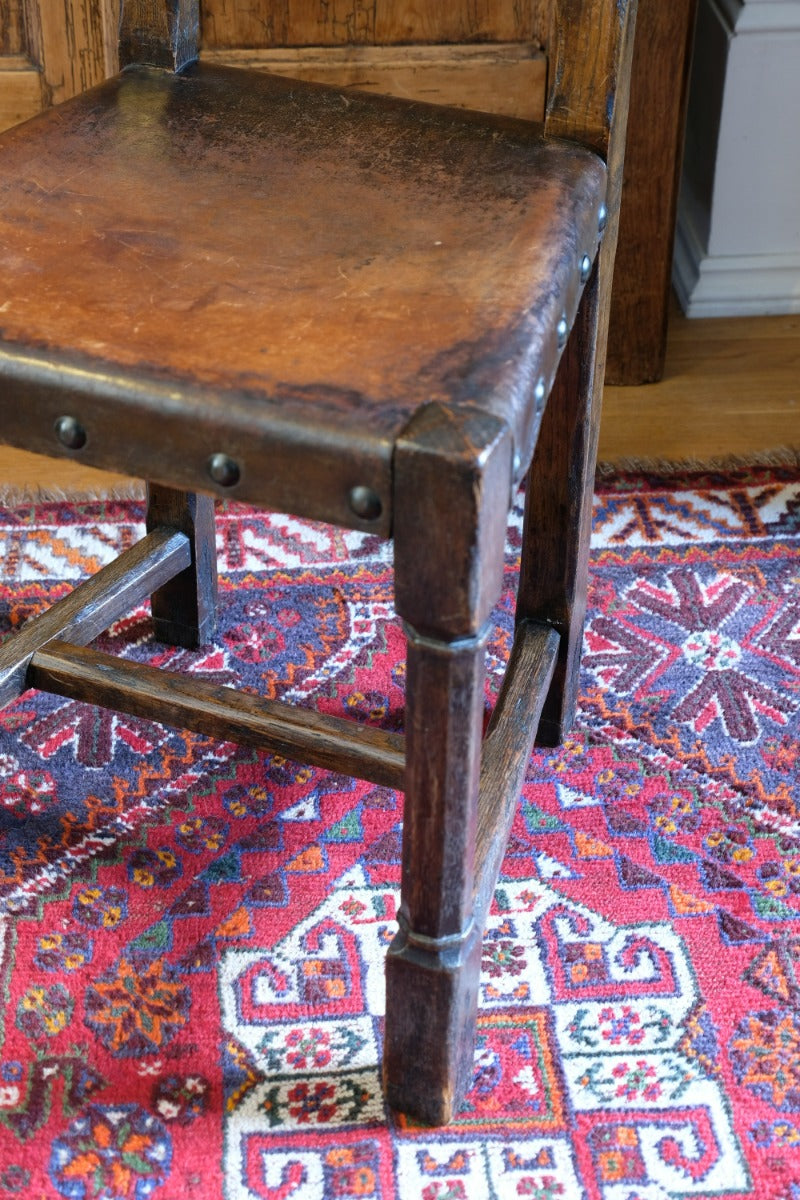 Hide upholstered seat with brass studs on antique elm chair