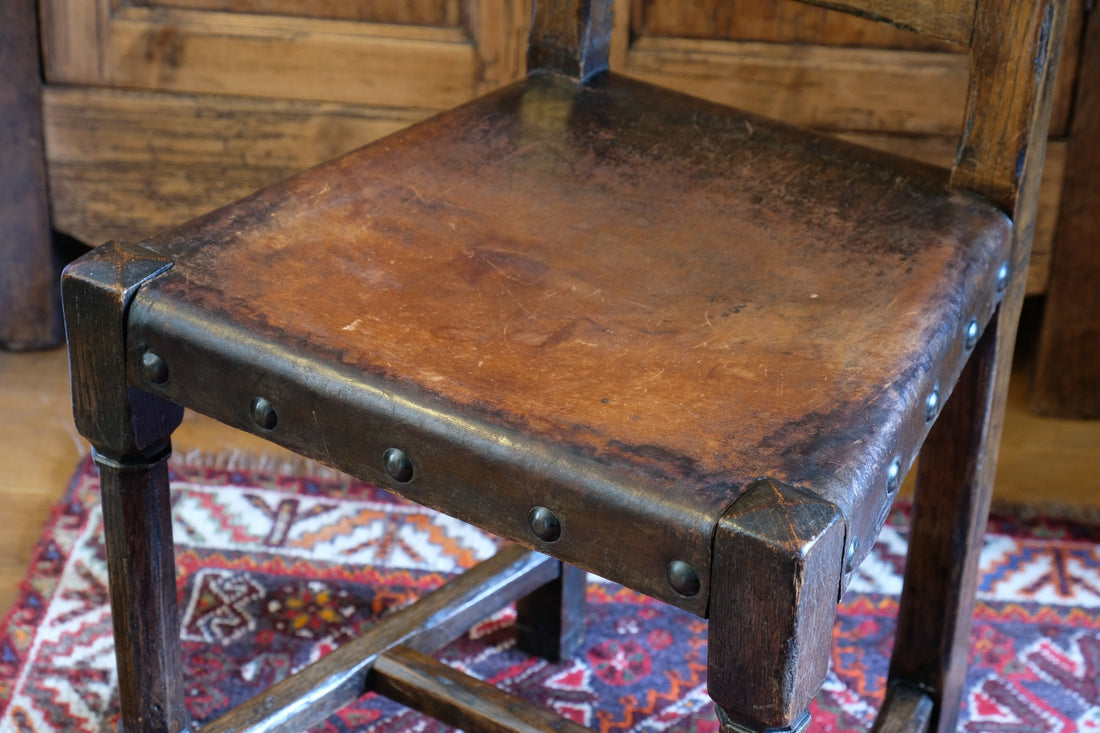 Hide upholstered seat with brass studs on antique elm chair