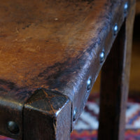 Hide upholstered seat with brass studs on antique elm chair