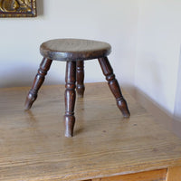 Antique English dairy milking stool with four turned legs and original dark painted finish