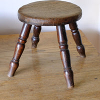 Antique English dairy milking stool with four turned legs and original dark painted finish