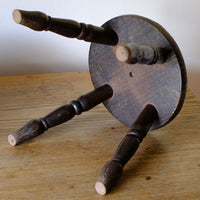 underneath of the Antique English dairy milking stool with four turned legs and original dark painted finish