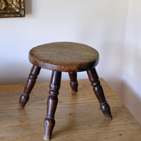 Antique English dairy milking stool with four turned legs and original dark painted finish