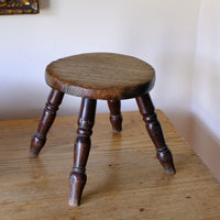 Antique English dairy milking stool with four turned legs and original dark painted finish
