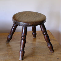 Antique English dairy milking stool with four turned legs and original dark painted finish