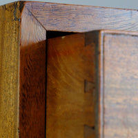 Close-up detail of a wooden cabinet corner showing the grain, finish, and internal dovetail joint construction. Late Georgian Anglo-Chinese Padauk Chest of Drawers with Mitred Face Frame and Original Brass Side Carrying Handles