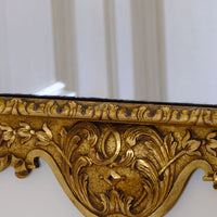 close up of A richly carved lower apron with flowing foliate scrollwork centred by a faceted diamond motif. Edwardian Queen Anne Revival carved giltwood wall mirror with Prince of Wales feather crest, c.1900