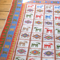 Handwoven Persian Sumak rug featuring colourful stylised goat motifs and geometric borders