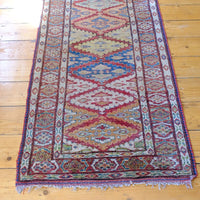 Tasselled ned of the Mid-20th Century North-West Persian ivory ground hand-knotted wool runner with fourteen hooked lozenge medallions