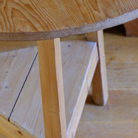 The three splayed legs are particularly well considered, each worked to an unusual faceted profile with a pronounced V-shaped front and softened chamfered rear, creating an irregular lozenge-like section. The changing planes catch the light and visually lighten the structure while retaining the timber required for the substantial pegged joints.