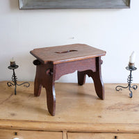 Antique Arts and Crafts oak low stool with S-shaped carrying handle, fret-cut arches and exposed keyed through-tenons, circa 1900.