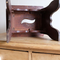 Underside of the Antique Arts and Crafts oak low stool with S-shaped carrying handle, fret-cut arches and exposed keyed through-tenons, circa 1900.