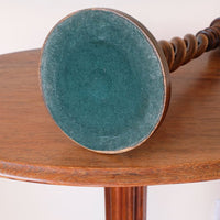 Worn green baize beneath the weighted base of an antique oak candlestick