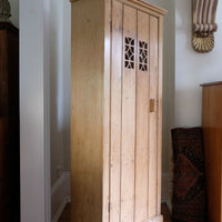 Antique pine cupboard, circa 1890–1910, with a boarded door, two pierced ventilation panels and a plinth base