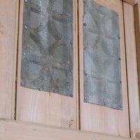 Perforated metal sheeting fixed behind the pierced ventilation panels of an antique pine cupboard