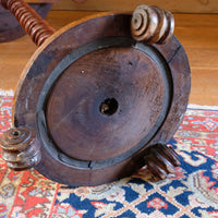 Underside of mid-Victorian burr walnut candle stand showing the segmented lead-weighted ring within the circular platform base