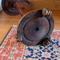 Underside of mid-Victorian burr walnut candle stand showing the segmented lead-weighted ring within the circular platform base