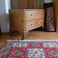 Side view of mahogany campaign chest showing carrying handle and shaped bracket feet
