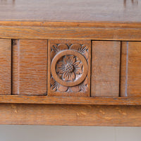 Close up of the carved Yorkshire Rose on a Arts & Crafts oak console table by Beresford & Hicks with two drawers and shaped trestle supports