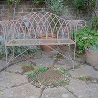 Painted wrought iron garden bench with Gothic arch back, scroll armrests and slatted seat
