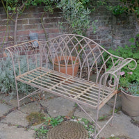 Painted wrought iron garden bench with Gothic arch back, scroll armrests and slatted seat