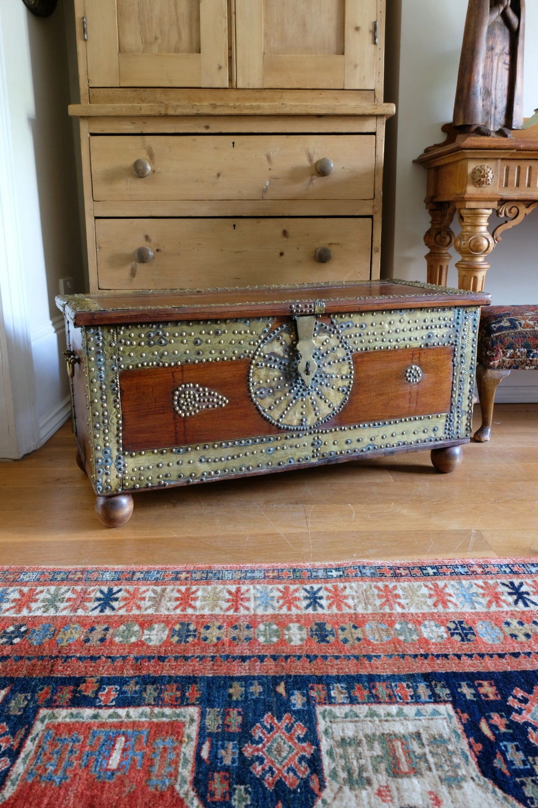 Teak Zanzibar chest decorated with brass studs raised on bun feet