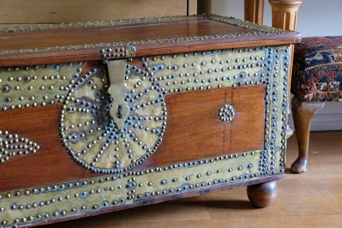Teak Zanzibar chest decorated with brass studs raised on bun feet